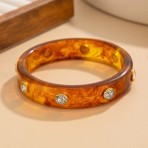 Détail d'un bracelet en résine écaille d'ambre avec strass scintillants sertis d'or