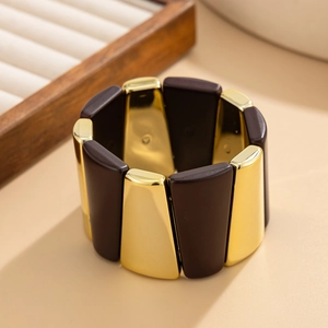 Détail d'un bracelet large extensible aux blocs trapézoïdaux polis marron et dorés alternés