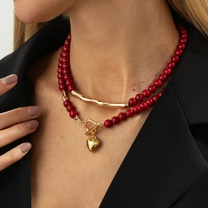 Detail of red beaded layered necklace with heart pendant and T-bar clasp on model