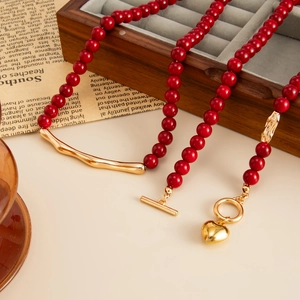 Detail of red bead necklace with heart pendant, golden OT buckle and metal accents