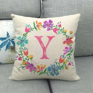 Federa in lino con ghirlanda floreale e lettera Y rosa su divano grigio
