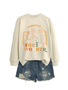 Flat lay of cream sweatshirt with floral text and blue distressed denim shorts