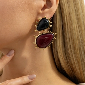 Close-up of retro geometric earrings with black and burgundy resin on a model
