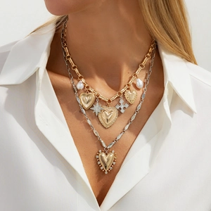 Detail of layered gold and silver chains featuring heart, star, cross, and pearl charms
