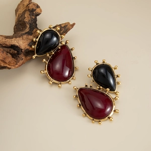 Detailed close-up of vintage drop earrings with red and black gems and gold beaded edges