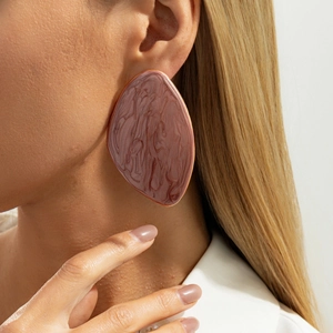 Detail of vintage resin earring with marble texture and golden metal edge on model