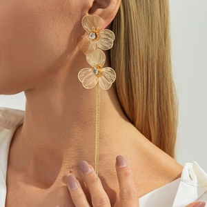 Detailed side view of long gold tassel earrings featuring two hollow metal flower charms