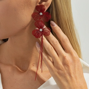 Detailed macro view of long red woven flower tassel earrings featuring bright zircon centers