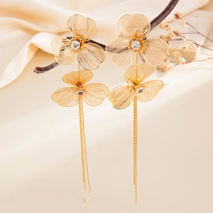 Golden ginkgo leaf flower tassel earrings with crystals on a luxury silk backdrop