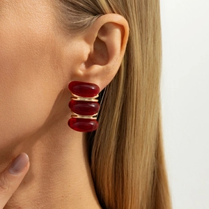 Detail view of retro earrings with three deep red oval stones and golden metal rings