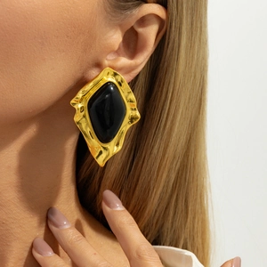 Macro shot of large vintage irregular gold metal earrings with black resin inlay