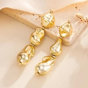Detail view of gold lava-textured earrings with irregular organic metal drop shapes