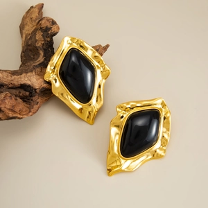 Detail of vintage French style gold earrings with black stone on a natural wood background