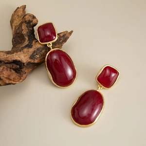 Detail of vintage French style gold earrings with inlaid deep red gemstones and retro design