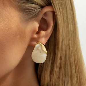 Detail of French vintage gold drop earring with white marble stone on female model