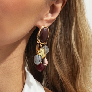 Close-up of vintage earrings with multi-color stones and a drop pearl on model