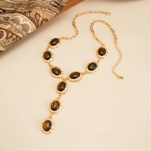 Vintage Y-shaped necklace with tiger eye stones on gold-plated chain over beige background