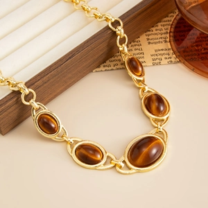 Macro detail of retro gold chain with oval tiger eye resin stones on a wooden stand