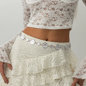Detail of silver hammer-textured metal coin body chain on white lace skirt outfit