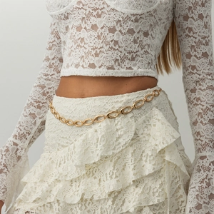Detail of irregular hollow gold metal waist chain on white lace garment for women