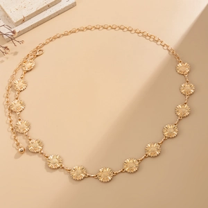 Close-up of golden sunflower chain belt with adjustable lobster clasp on beige background