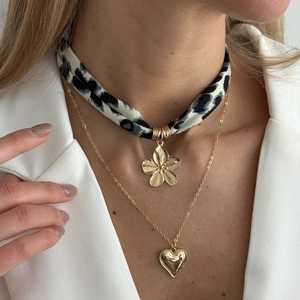Detail einer vergoldeten Halskette mit Leopardenmuster-Choker und Herz-Anhänger
