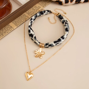 Detail von Leoparden-Choker mit goldenem Blumenanhänger und feiner Herz-Halskette