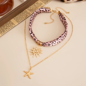 Details des pinkfarbenen Leoparden-Chokers und der Goldkette mit Sonnen- und Seesternanhänger