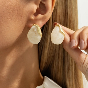 Modern oversized marble resin stud earrings with golden metal frames shown on model