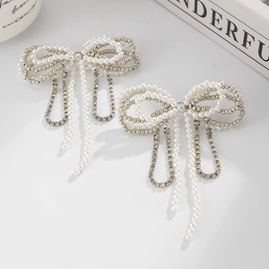 Detailed view of pearl bow earrings with silver tassels and sparkling rhinestone accents