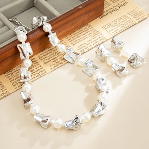 Detail van ketting met onregelmatige zilveren kralen en bijpassende oorbellen
