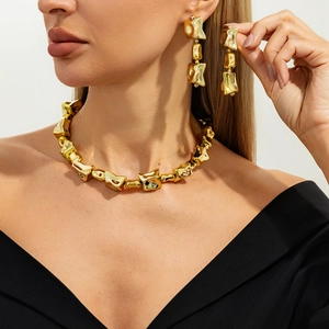 Close-up van een model met een onregelmatige geometrische gouden ketting en oorbellen set