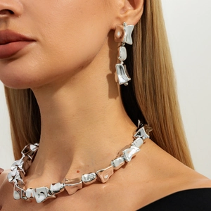 Detailopname van de onregelmatige zilverkleurige grove ketting en oorbellen bij een model