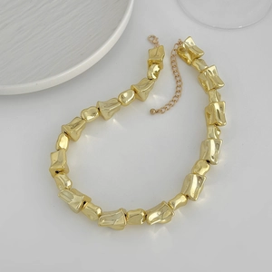 Detail van gouden onregelmatige blokketting met metalen textuur en verstelbare sluiting