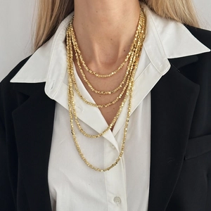 Close-up of a layered gold cube bead necklace worn with a blazer for a minimalist look