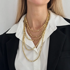 Detail of layered gold square bead necklace styled with a white shirt and black blazer