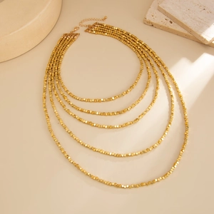 Detail of five-layer gold beaded necklace with cube charms and adjustable clasp