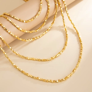 Detailed view of layered minimalist golden square bead necklace with rich metallic luster
