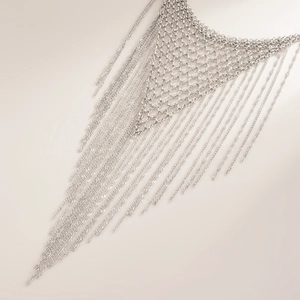 Detail of silver mesh body chain with long tassels showing intricate metal weaving and texture