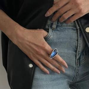 Close-up of elegant large blue gemstone ring on model finger with stylish denim outfit