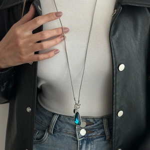 Detail of silver long snake chain with blue teardrop crystal pendant and OT buckle toggle