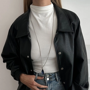 Long silver necklace with blue teardrop gemstone pendant on a white turtleneck sweater