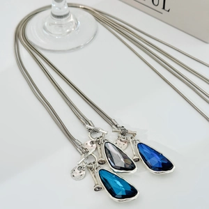Detail of three-piece teardrop crystal necklace set with silver toggle clasp and charms