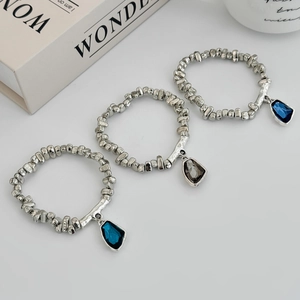 Detail of silver bangles with geometric blue and grey crystal charms on a clean surface