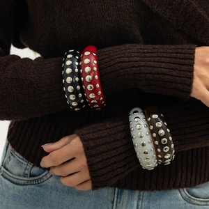 Detail of studded resin bangles in black, red, white, and amber colors on a model
