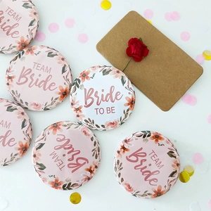 Close-up of Team Bride and Bride To Be badges with floral patterns for wedding parties