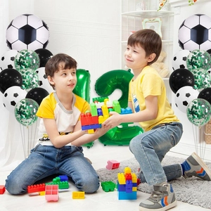 Enfants jouant près de ballons de foot avec chiffre 12 vert pour fête d'anniversaire