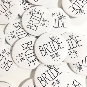 Primo piano di distintivi in latta bianchi Bride to Be impilati con icona anello di diamante