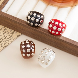 Close-up of four retro resin wide rings with metallic studs in a wooden jewelry box