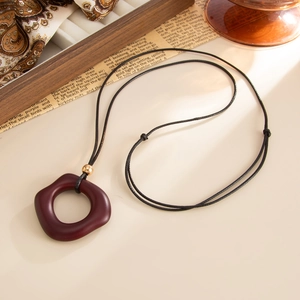 Close-up of a burgundy irregular round wooden pendant with black cord on vintage decor
